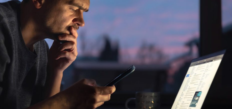 A young man works on a laptop. Man with laptop. High quality photo. A man works on a laptop in the evening. Space for text. The man works at home.